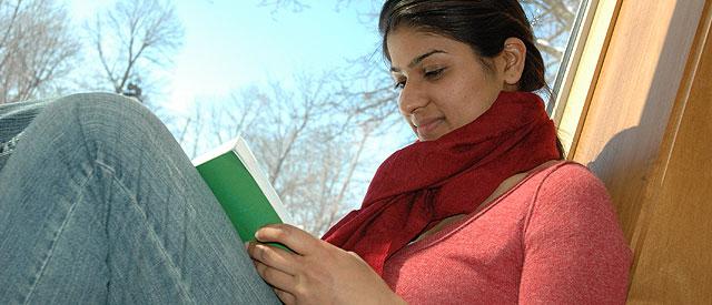 A girl reading a book in a sunny window